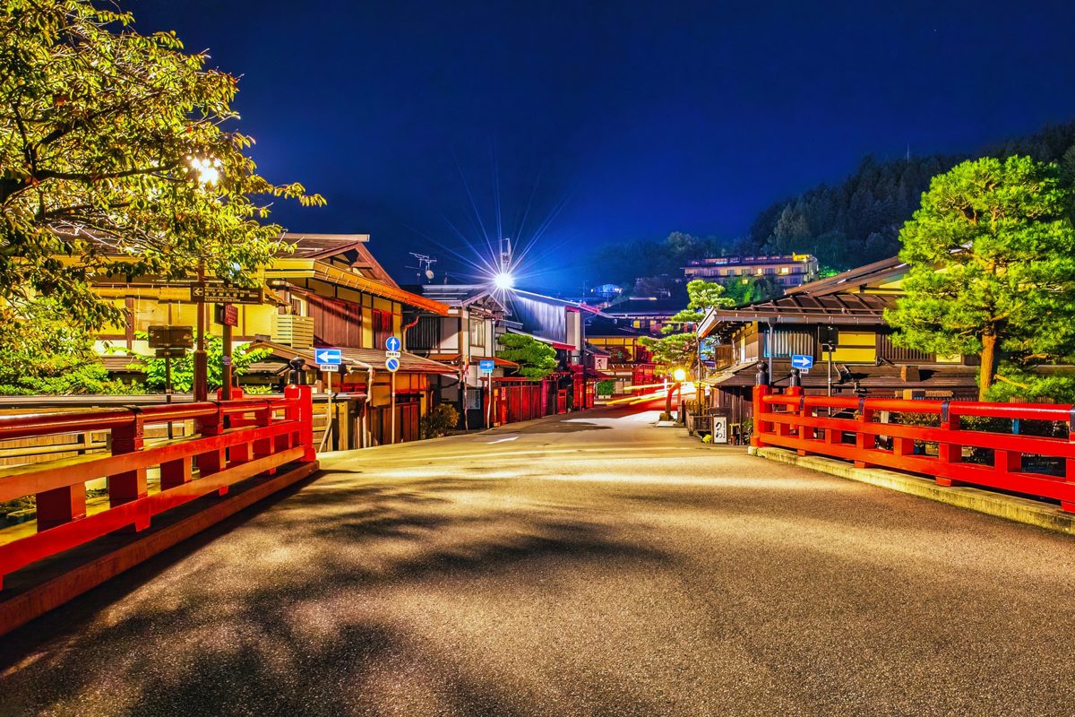 Old-town streets and red bridge railings glowing at night
